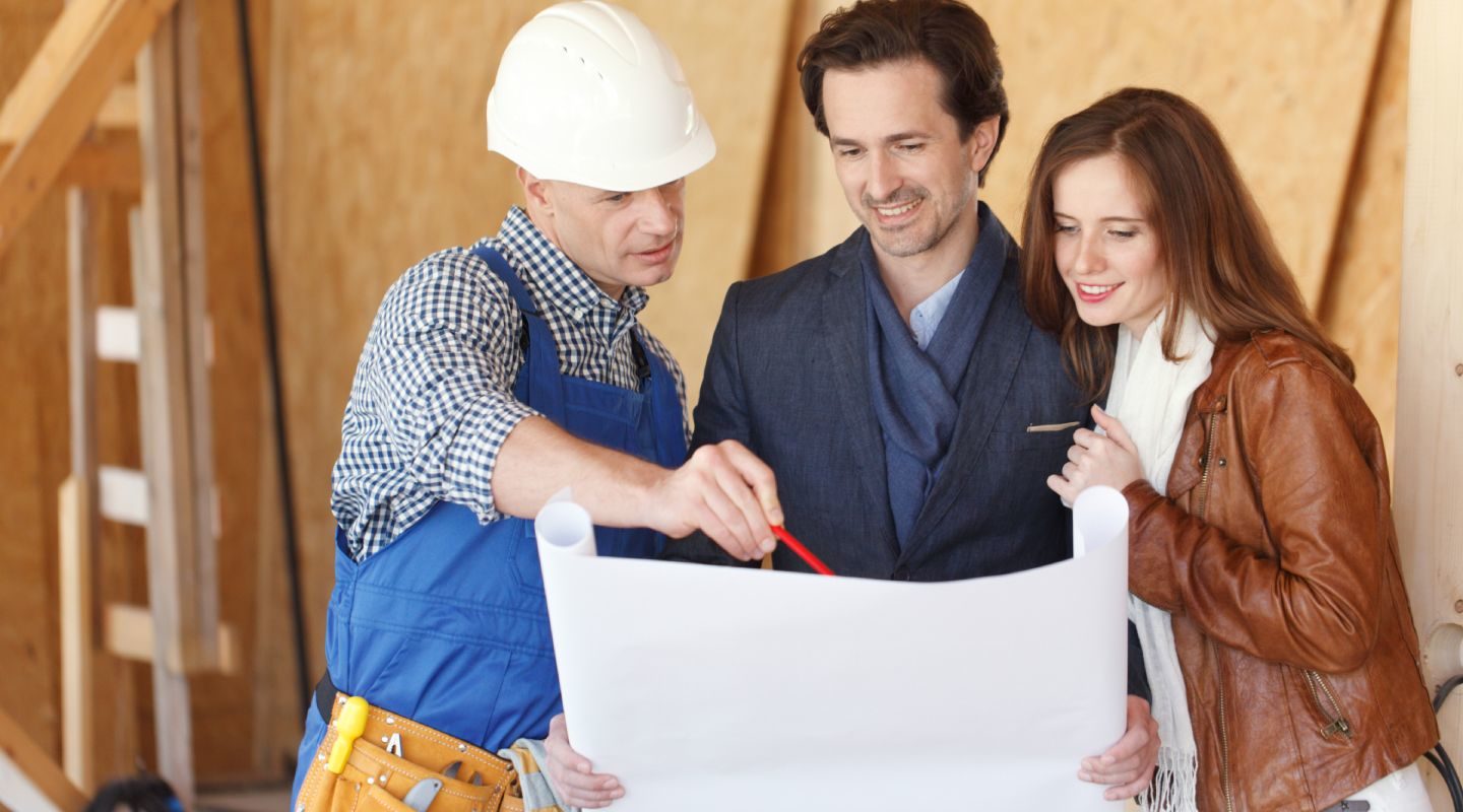 Foreman showing house design construction plan to a happy young couple new house real estate concept