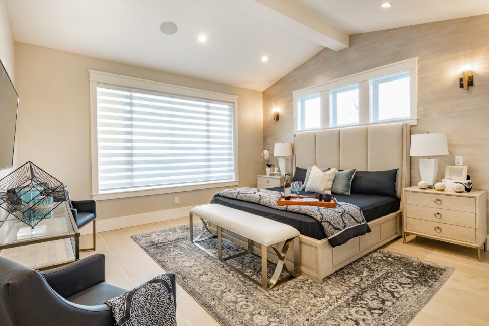 master bedroom with large windows black linens staged with wine and glasses
