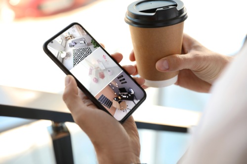 Man monitoring modern CCTV cameras on smartphone indoors, closeup. Home security system