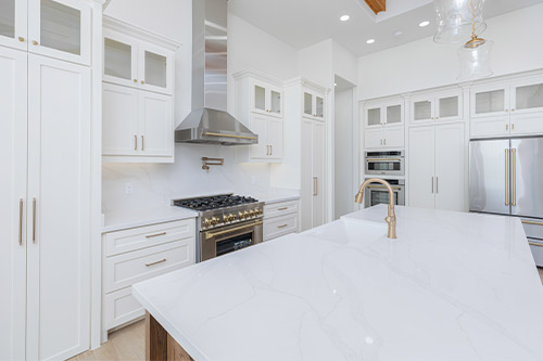 A modern kitchen featuring white cabinets and a sleek stainless steel oven, showcasing current design trends. Guzman Construction